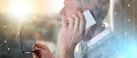 Senior businessman talking on mobile phone and looking through the window, light effect, overlayed...