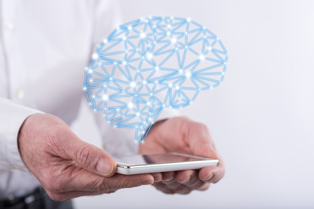 Artificial intelligence concept above a smartphone held by handsの写真素材