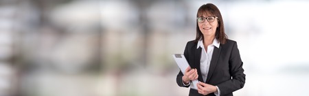 Portrait of mature businesswoman holding a clipboard on blurred background