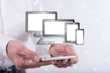 Technology devices concept above a smartphone held by hands