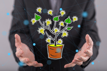 Green energy concept above the hands of a man in backgroundの写真素材