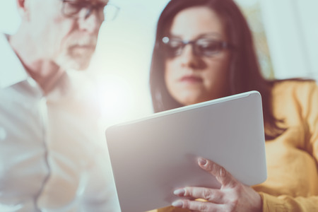Young businesswoman and senior businessman working together at office, light effectの写真素材