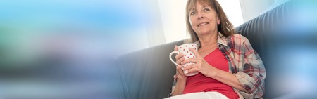 Smiling mature woman relaxing on sofaの写真素材