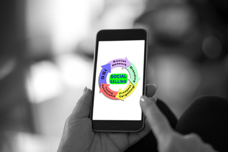 Hand holding a smartphone with social selling conceptの写真素材