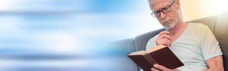 Portrait of thoghtful mature man reading a book at home, light effectの写真素材