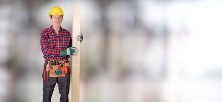 Building worker with tool belt and wood board on blurred backgroundの写真素材