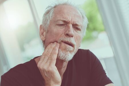 Portrait of mature man with toothache at home