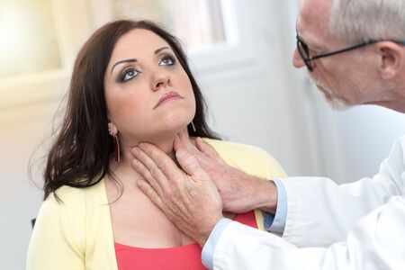Doctor checking thyroid of a young patient, light effectの写真素材