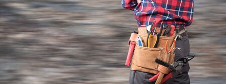 Building worker with tool belt on blurred background