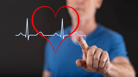 Man touching a heart beats graph on a touch screen with his fingerの写真素材
