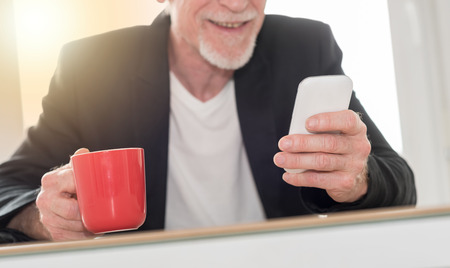 Senior man using his phone at home, light effect