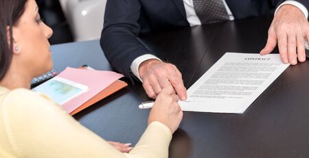 Young woman signing contract with financial adviserの写真素材