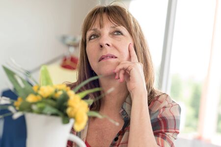 Portrait of pensive mature woman at homeの写真素材