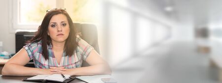 Portrait of young businesswoman sitting at desk in office, light effectの写真素材