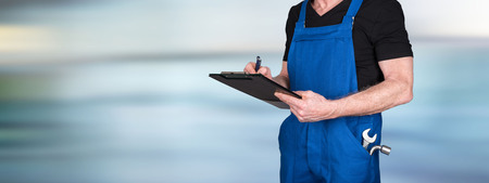Car mechanic taking notes on clipboard on blurred backgroundの写真素材