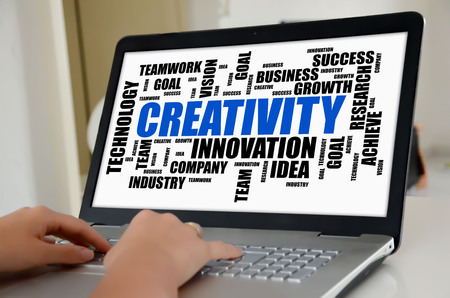 Hands on a laptop with screen showing creativity word cloud conceptの写真素材