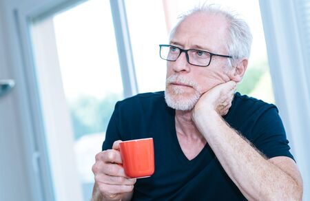Portrait of pensive mature man holding a cup of coffee
