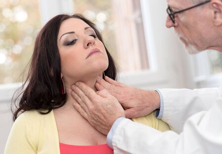 Doctor checking thyroid of a young patientの写真素材