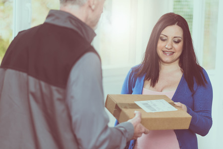 Pretty woman receiving package from delivery manの写真素材