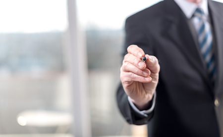 Businessman pointing a pen on a virtual screen, selective focusの写真素材