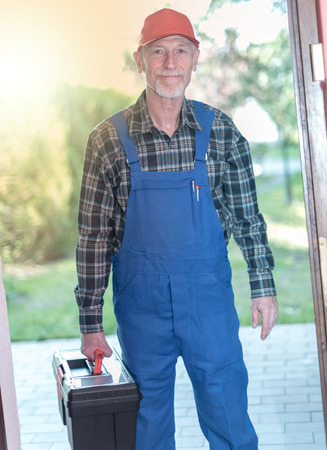 Portrait of a senior repairman holding his toolbox, light effectの写真素材