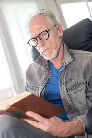 Portrait of mature man reading a book at homeの写真素材