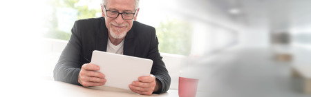 Portrait of happy senior businessman working on tabletの写真素材
