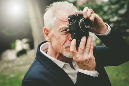 Mature man taking pictures outdoors, light effect