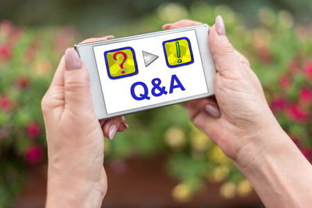 Female hands holding a smartphone with q&a conceptの写真素材