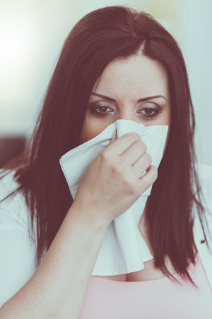 Portrait of young woman blowing her noseの写真素材