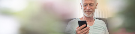 Portrait of mature man listening music with earphones at home, light effect