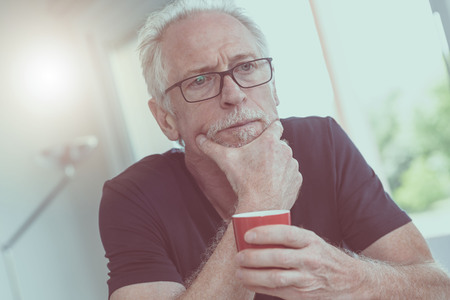Portrait of pensive mature man holding a cup of coffee