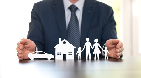 Insurer protecting a family, a house and a car with his handsの写真素材