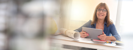 Portrait of female architect working on plans at office, light effet
