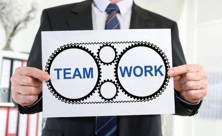 Paper showing teamwork concept held by a businessmanの写真素材