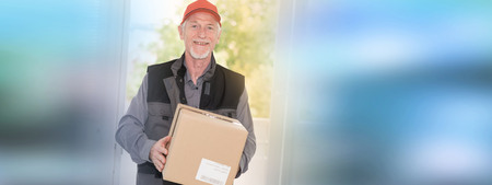 Portrait of smiling senior deliverer holding a packageの写真素材