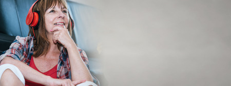 Happy mature woman listening to music at homeの写真素材