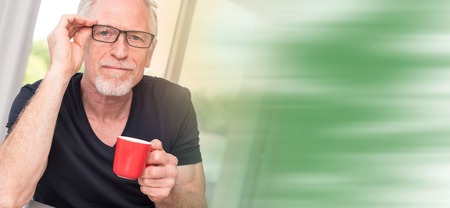 Portrait of smiling mature man holding a cup of coffee, light effectの写真素材