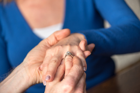 Man putting a diamond ring on woman's fingerの写真素材