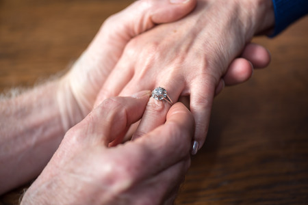 Man putting a diamond ring on woman's fingerの写真素材