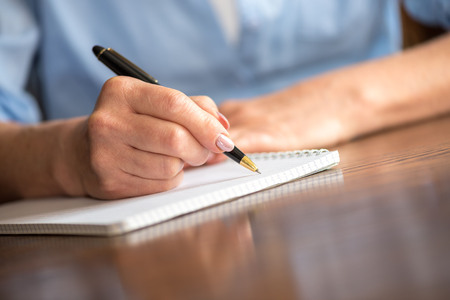 Woman with pen writing on notebook