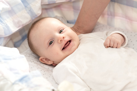 Portrait of cute smiling baby girl lying in her cribの写真素材