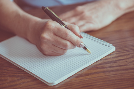 Female hand with pen writing on notebookの写真素材