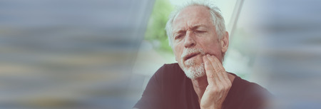 Portrait of mature man with toothache at homeの写真素材