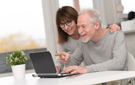 Happy mature couple having an amazing surprise on laptopの写真素材