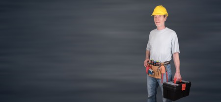 Portrait of building worker with tool belt and helmet on blurred backgroundの写真素材