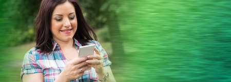 Pretty young woman using her mobile phone in a parkの写真素材