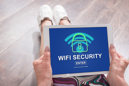 Woman sitting on the floor with a tablet showing wifi security conceptの写真素材