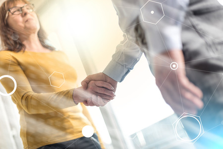 Businesswoman and businessman shaking hands in office, light effect