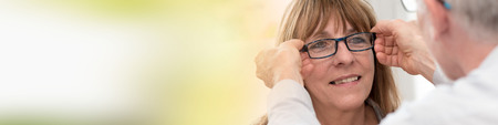 Mature woman testing new eyeglasses in optician storeの写真素材